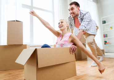 couple with cardboard boxes having fun at new home