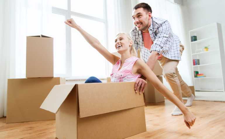 couple with cardboard boxes having fun at new home