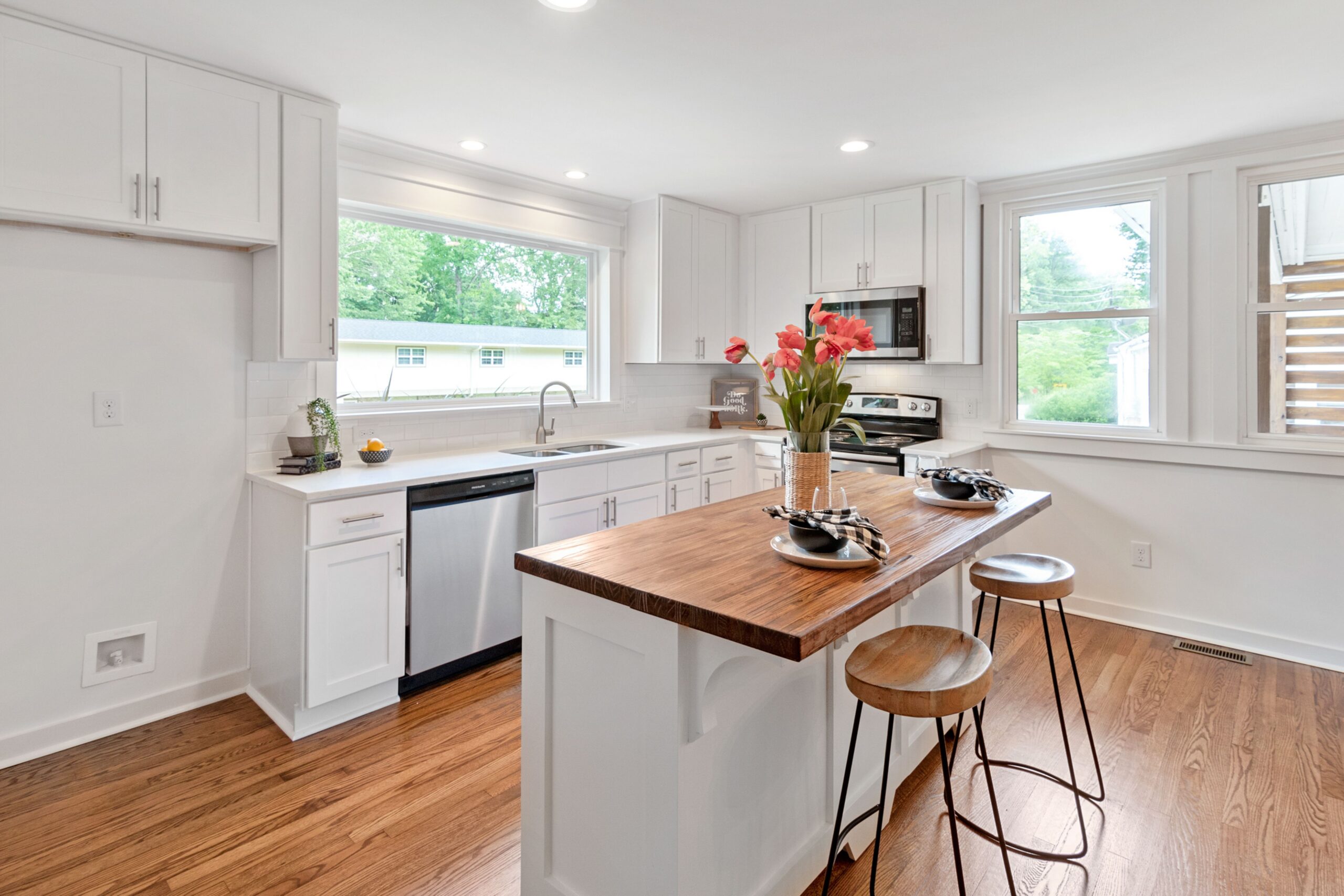 A well lit modern kitchen with white cabinets and an island
