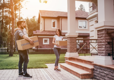 Couple moving in to new home holding boxes