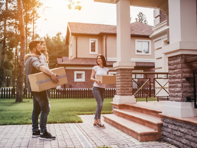 Couple moving in to new home holding boxes