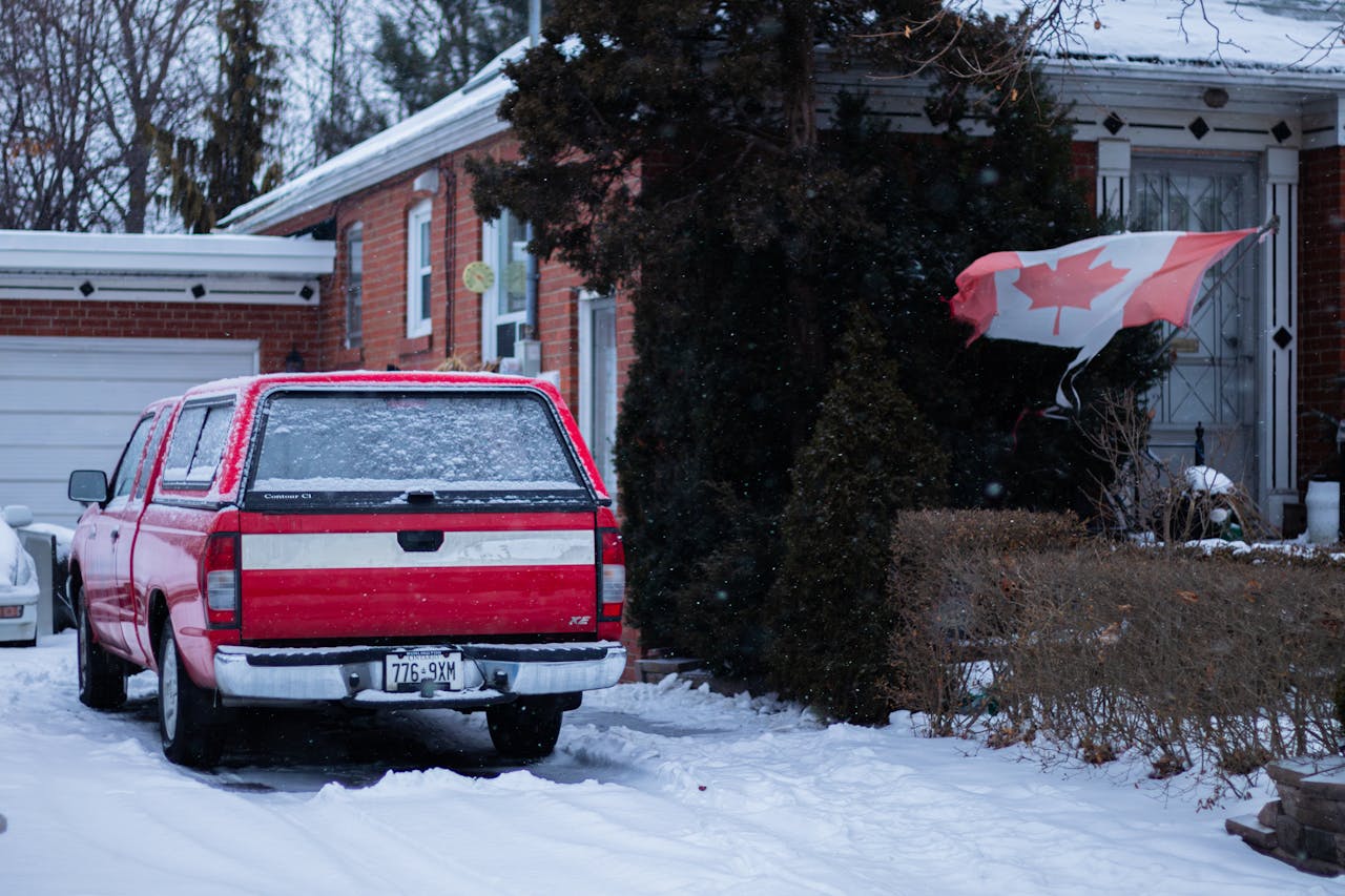 Canadian flag, snowy driveway, red SUV, brick house