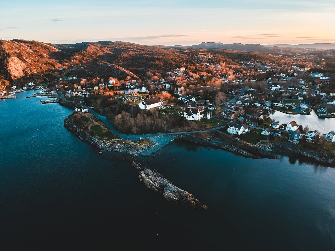 Aerial view of Marysvale, Canada, rocky ocean shoreline, suburb, houses, hills at sunset
