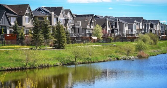 Canadian suburb, row of houses near water, clear sky, green grass