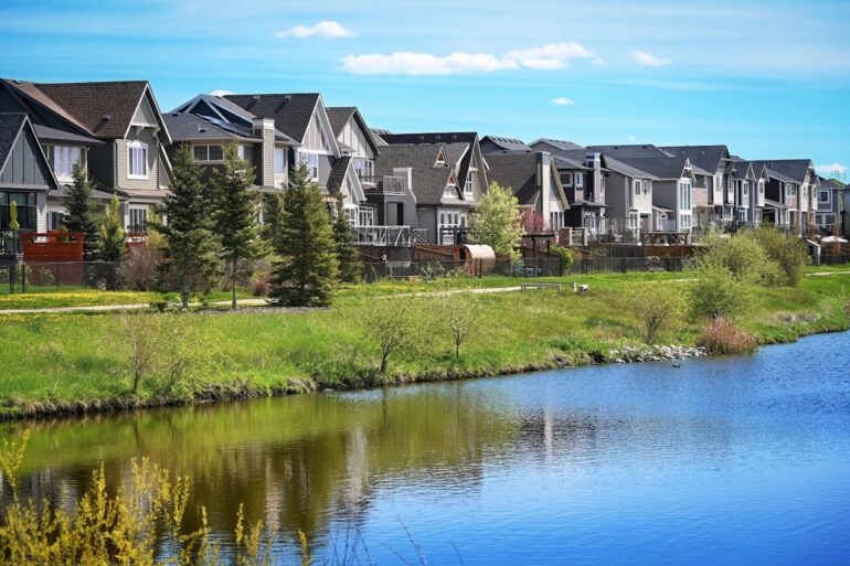 Canadian suburb, row of houses near water, clear sky, green grass